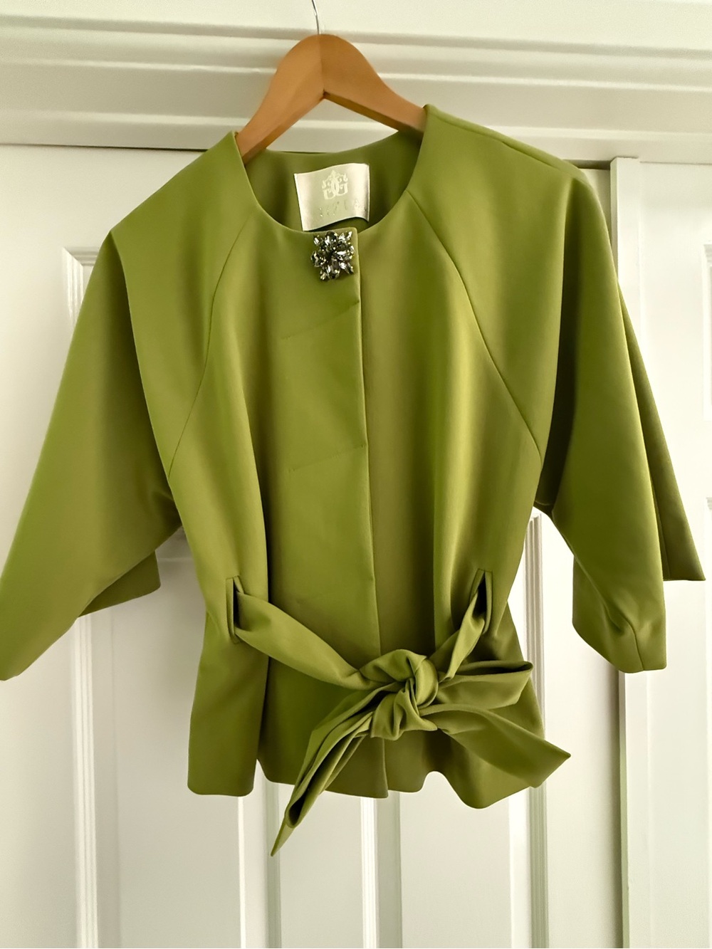Short sleeve tie front jacket with a jewel encrusted collar clasp .